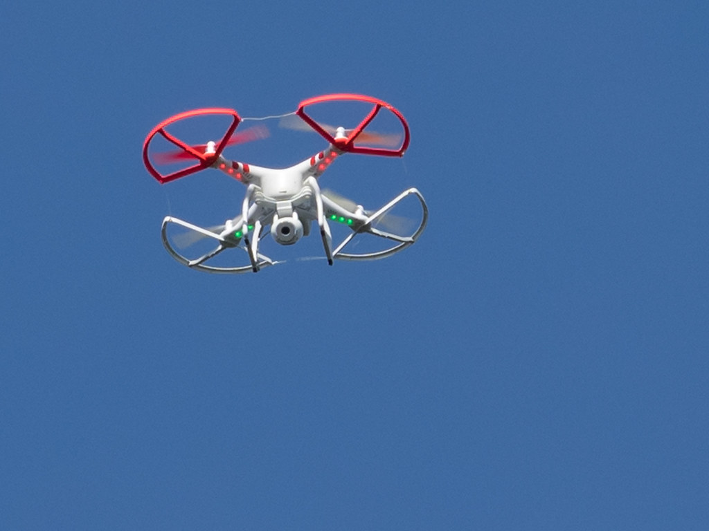 Fliegende Vermessungsdrohne mit Kamera vor blauem Himmel